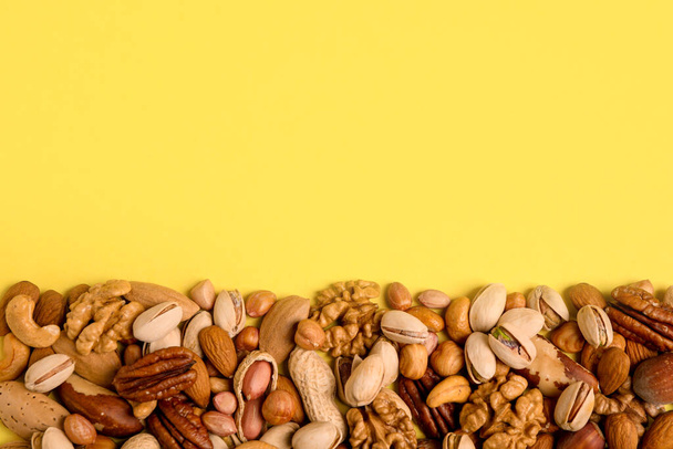 Different delicious nuts on yellow background, flat lay. Space for text - Photo, image