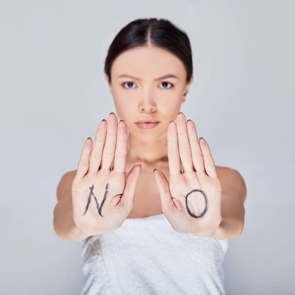 Woman expressing denial with NO on her hand. - Foto, imagen
