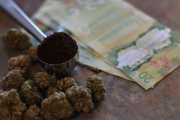 schepje koffie naast wiet of marihuana en biljetten van twintig dollar - Foto, afbeelding