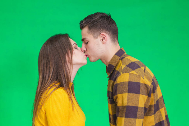 Happy calm man and woman enjoying peace of mind and kissing against green background. - Foto, imagen