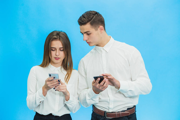 Business people using smartphones, completing some work tasks against blue background. - Фото, изображение