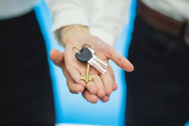 Cropped shot of realtors hands holding keys to perfect apartment over blue background. - Photo, Image
