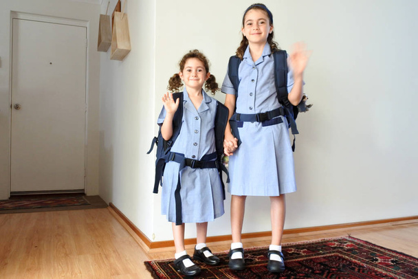 Две счастливые сестры машут на прощание перед тем, как пойти в школу
 - Фото, изображение
