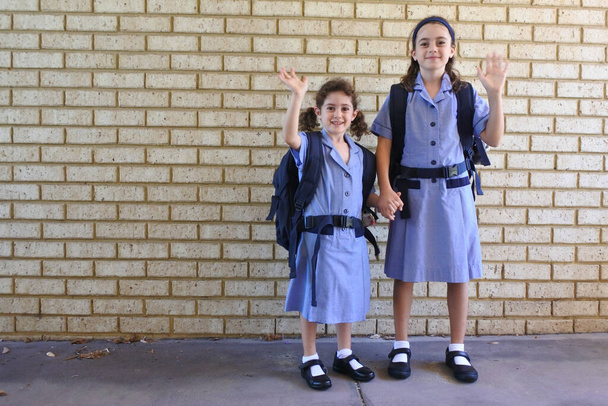 Две счастливые сестры машут на прощание перед тем, как пойти в школу
 - Фото, изображение