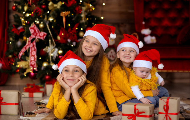 Children smiling in red hats on the background of the Christmas  - Фото, зображення