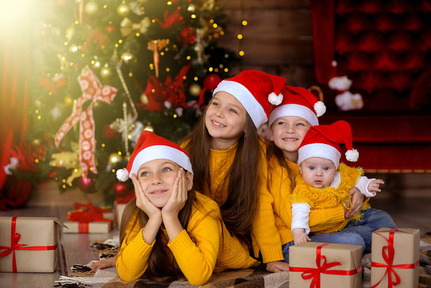 Gyerekek mosolyognak piros kalapban a háttérben a karácsony  - Fotó, kép