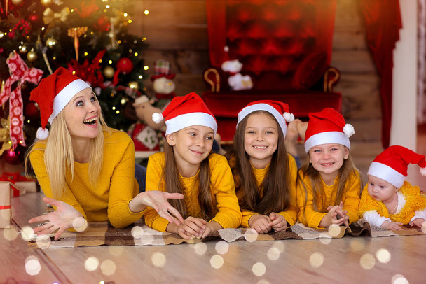 Мама з дітьми в червоних капелюхах на задньому плані Різдва.  - Фото, зображення