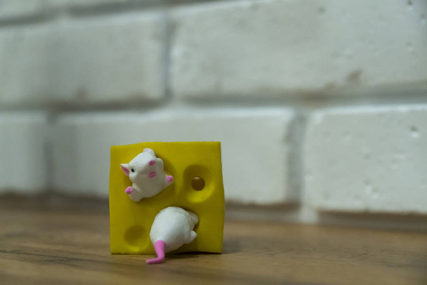 Speelgoedmuizen en kaas. ratten kruipen over een stuk kaas - Foto, afbeelding