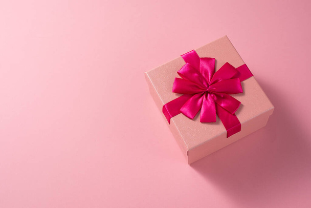 Valentine's Day celebration concept. A nice gift from a loved one. Box with a bow on a delicate pink background. Copy space. Flat lay. Close-up. - Foto, afbeelding