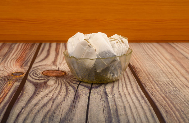Teebeutel in einer Glasvase auf einem hölzernen Hintergrund. Nahaufnahme. - Foto, Bild