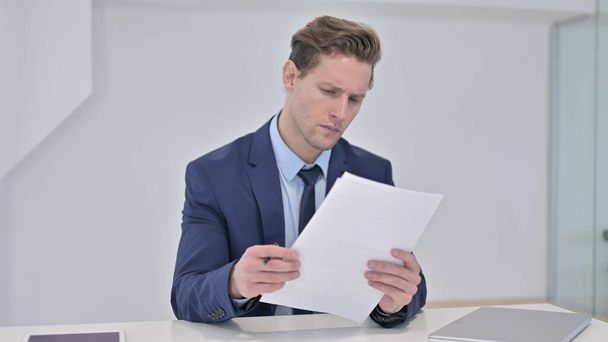 Młody biznesmen Czytanie dokumentów w biurze - Zdjęcie, obraz