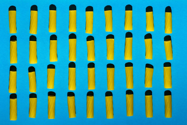 Makaroni on järjestetty riveihin sinisellä pohjalla
 - Valokuva, kuva