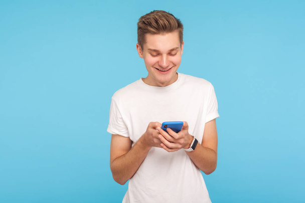 Portrait of happy man in white t-shirt using cellphone with chee - Zdjęcie, obraz