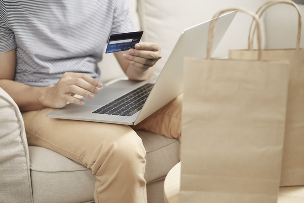 Man online winkelen met behulp van laptop en terug creditcard e portemonnee een - Foto, afbeelding
