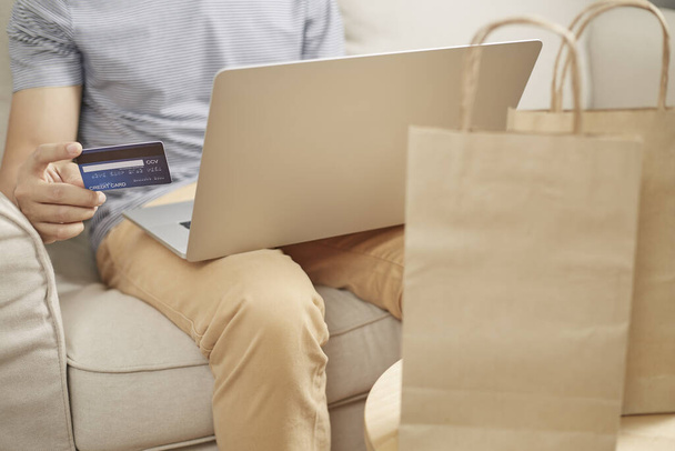 Człowiek zakupy online za pomocą laptopa i tylnej karty kredytowej e portfel - Zdjęcie, obraz