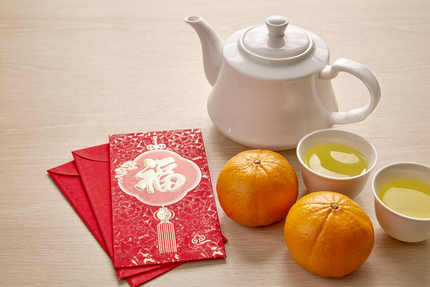 Chinesisches Neujahrs- und Mondfest mit Goldbarren, rotem Umschlag, Orange und heißem Tee. (mit dem Buchstaben "fu", was Glück, Wohlstand und Frühling bedeutet. - Foto, Bild