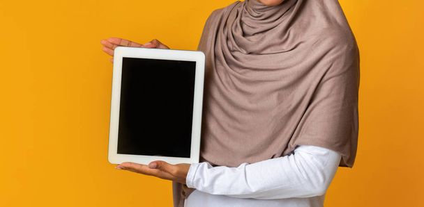 Mujer irreconocible en pañuelo para la cabeza sosteniendo tableta digital con pantalla negra, maqueta
 - Foto, imagen