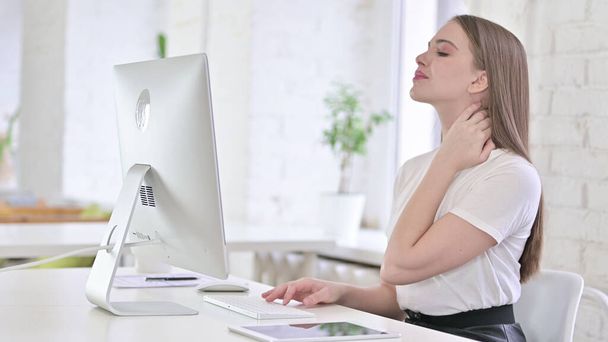 Jonge vrouw met nekpijn in kantoor - Foto, afbeelding