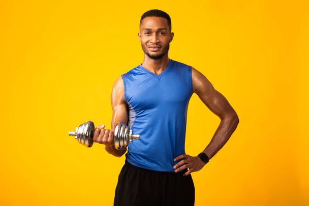 African bodybuilder pumping up biceps with dumbbells - Φωτογραφία, εικόνα