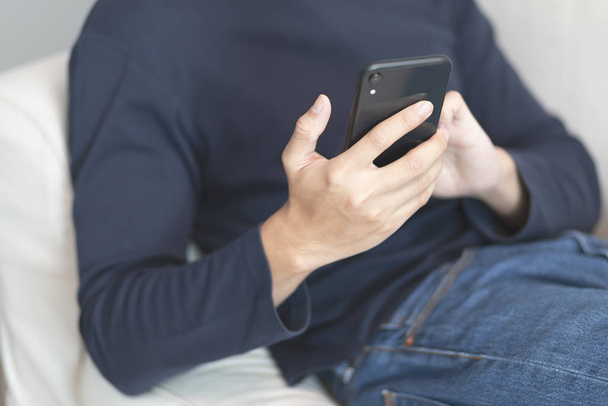 Чоловік у синій футболці розслабляється і використовує мобільний телефон
 - Фото, зображення