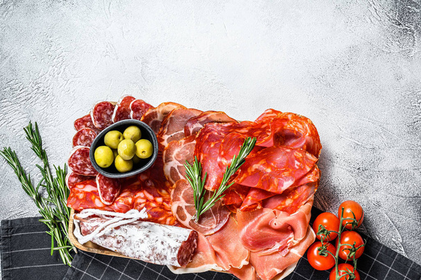 Cured meat platter of traditional Spanish tapas. Chorizo, jamon serrano, lomo and fuet. Gray background. Top view. Copy space - Foto, Imagem
