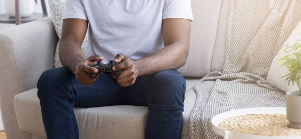 Африканець грає у відеоігри з джойстиком вдома. - Фото, зображення
