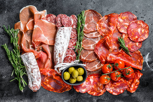 スペインの冷たい肉の品揃え。チョリゾ、フエ、ロモ、ジャモン・イベリコ、オリーブ。黒の背景。トップ表示. - 写真・画像