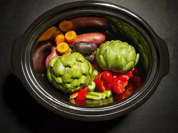Grande casserole noire avec des légumes sur elle prête à cuire
 - Photo, image