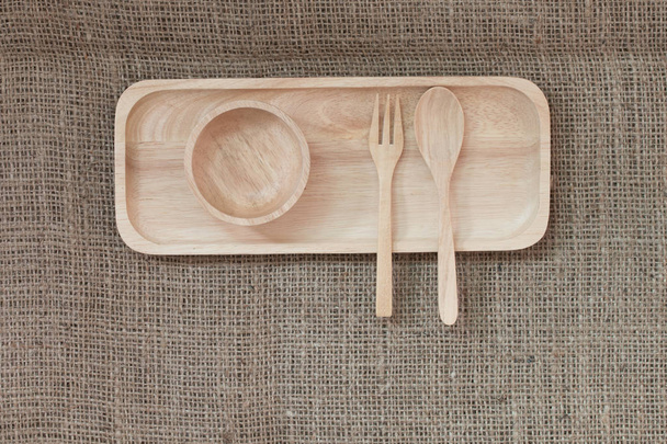 cuillère en bois et bol en bois dans un plateau en bois sur fond de texture de toile
. - Photo, image