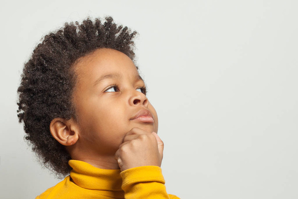 Vähän fiksu utelias musta lapsi poika ajattelee valkoisella taustalla
 - Valokuva, kuva