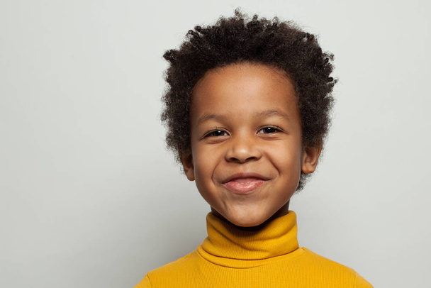 Mischievous zwart kind jongen glimlachen op witte achtergrond - Foto, afbeelding