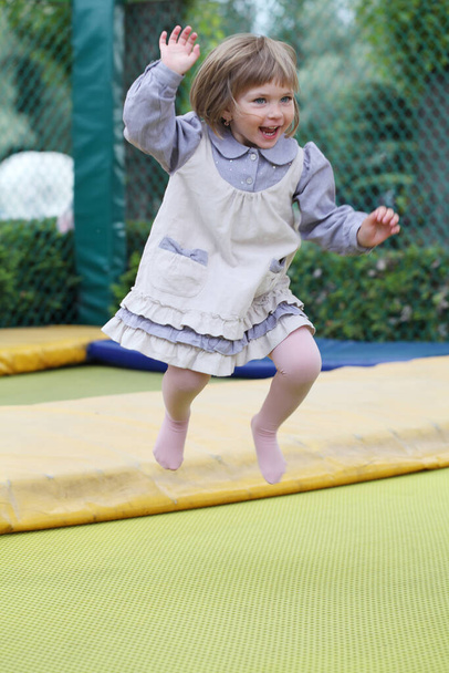 Petite fille sur une aire de jeux dans un parc, sautant sur un trampoline Petite fille sur un trampoline
.  - Photo, image