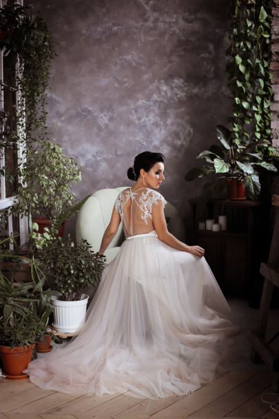 エレガントなドレスを着た美しい花嫁がソファの上に座っています  - 写真・画像