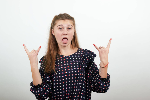 girl in black dress shows her fingers cool looking rock symbol stuck out tongue - 写真・画像