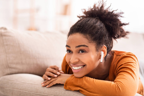 Sonriente chica afroamericana escuchando música relajante en casa
 - Foto, Imagen