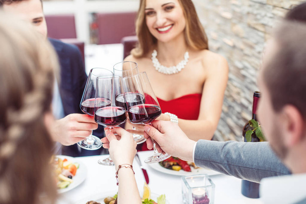 赤ワインで乾杯するレストランのテーブルに座っている人 - 写真・画像