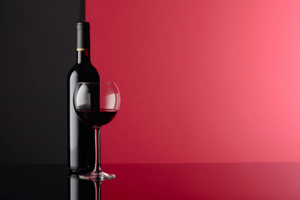 Glass and bottle of red wine on a black reflective background. C - Photo, Image