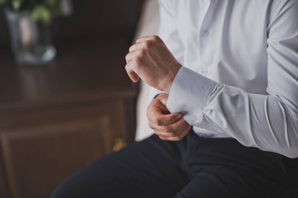 Fastening the cufflinks on the sleeve of his shirt 2411. - Foto, afbeelding