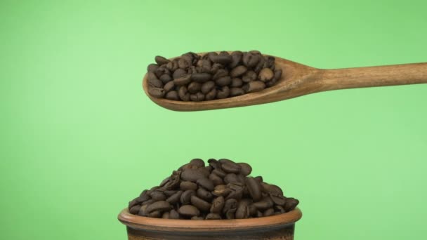Αργές κινήσεις. Οι κόκκοι του καφέ κοιμούνται αρκετά από μια ξύλινη κουτάλα σε ένα σωρό σπόρους σε ένα πήλινο μπολ.. - Πλάνα, βίντεο