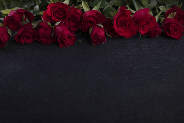 Valentine Day frame. Red roses on the upper edge on a dark background with a copyspace - Foto, imagen
