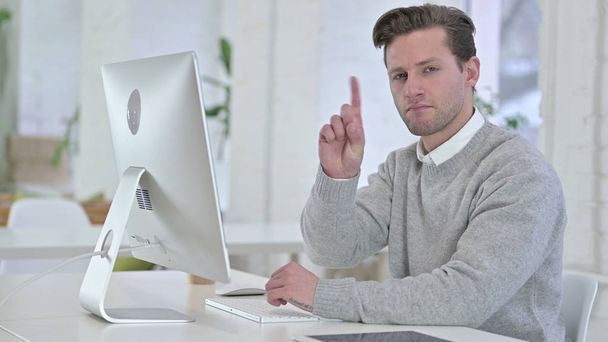 Fiatalember nemet mond Finger az irodában - Fotó, kép