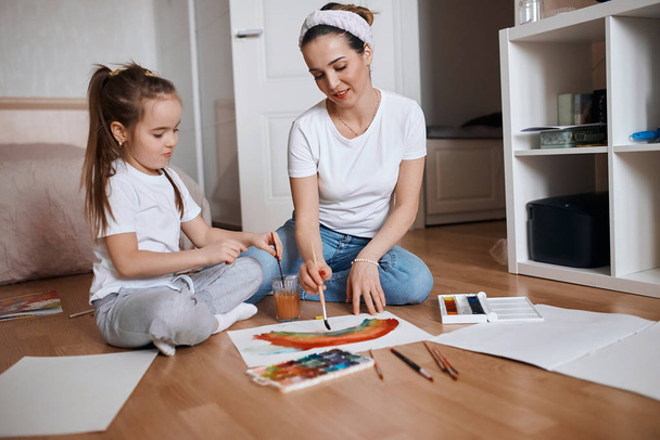 young teacher teaching girl to mix paints - Fotoğraf, Görsel