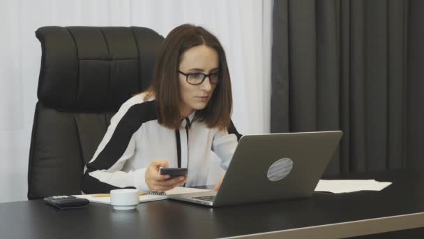 Business woman excited with good financial deal. Happy smiling woman celebrating successful job promotion in office. Female boss with phone enjoys finance results of company. Business success concept - Filmati, video