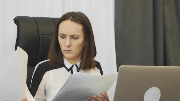 Shocked female boss looking at financial report. Worried businesswoman looks at company accounts. Upset woman watching at reports and worries about situation on financial stock market - Materiaali, video