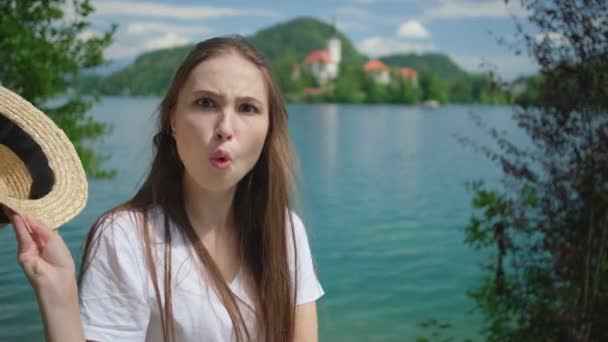 mujer está cambiando la expresión de la cara y la mueca en la orilla del lago Bled y la isla
 - Imágenes, Vídeo