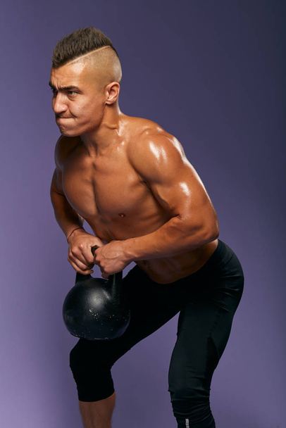 tensed strong man trying to keep the kettlebell - Fotó, kép
