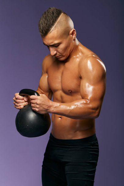 young man having kettlebell exercises at gym - Фото, изображение