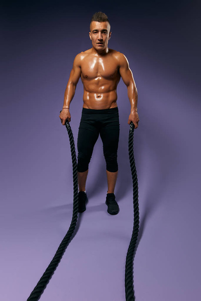 slim muscular man training with battle rope - Фото, зображення