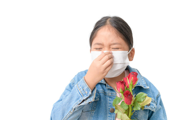 Παιδί με μάσκα για την πρόληψη αλλεργίας και κρατώντας κόκκινο τριαντάφυλλο  - Φωτογραφία, εικόνα