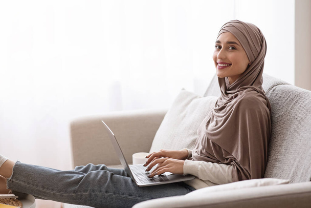 Улыбающаяся девушка в хиджабе с ноутбука дома, учится в Интернете
 - Фото, изображение